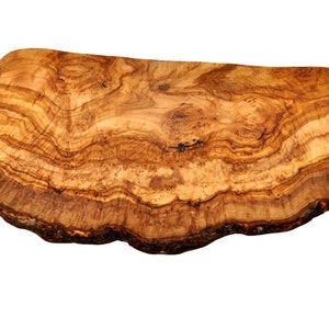 May include: A rectangular olive wood chopping board with rounded corners, featuring a prominent natural wood grain pattern in shades of light and dark brown, with a rough, textured bark edge along the bottom side of the board.
