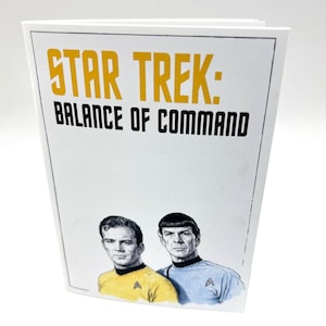 May include: A white book with the title "STAR TREK: BALANCE OF COMMAND" in yellow and black lettering. Below the title are illustrations of Captain Kirk and Spock in their Starfleet uniforms.