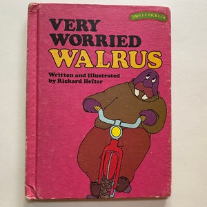 May include: A pink book cover with the title "Very Worried Walrus" in black and yellow lettering. The book is illustrated with a purple walrus riding a red bicycle.