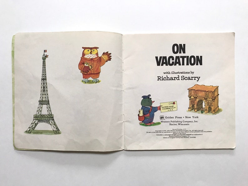 May include: An open book with the title "On Vacation" by Richard Scarry. The book features illustrations of an owl, a penguin, the Eiffel Tower, and the Arch of Constantine.