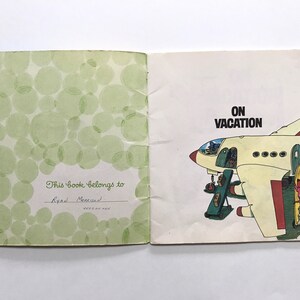 May include: A vintage children's book titled "On Vacation" with a green cover featuring a pattern of circles. The inside page shows a cartoon illustration of a plane with mice boarding the plane.
