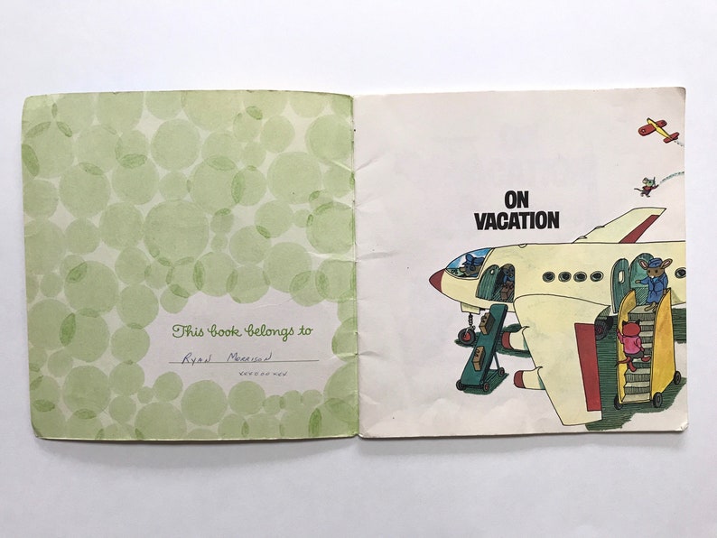 May include: A vintage children's book titled "On Vacation" with a green cover featuring a pattern of circles. The inside page shows a cartoon illustration of a plane with mice boarding the plane.