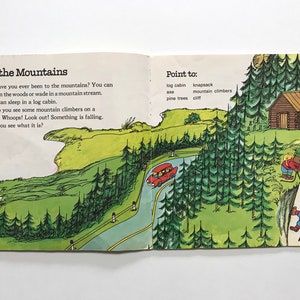 May include: An illustrated children's book page showing a red car driving on a winding road through a green forest. The text on the page reads "In the Mountains" and "Point to: log cabin, knapsack, mountain climbers, pine trees, cliff".