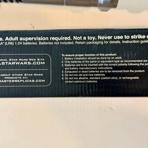 May include: Black product packaging with text including "12+ years. Adult supervision required. Not a toy." and "WWW.STARWARS.COM." Requires 6 AA batteries. Instructions included. The product is from Master Replicas.
