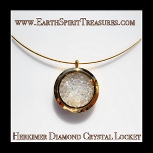 May include: A gold-toned necklace featuring a round pendant filled with Herkimer diamond crystals. The pendant is suspended from a thin, gold-colored chain. The text "www.EarthSpiritTreasures.com" and "Herkimer Diamond Crystal Locket" are displayed.
