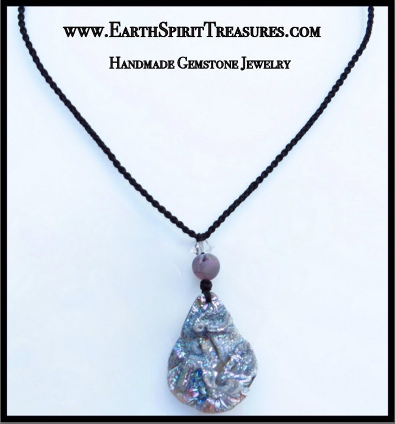 K&ouml;nnte beinhalten: Halskette mit einem handgefertigten Edelstein-Anh&auml;nger in Tropfenform mit schillernden Farben. Der Anh&auml;nger h&auml;ngt an einer schwarzen Kordel, mit einer lila Perle und einem klaren Kristall. Der Text "www.EarthSpiritTreasures.com Handmade Gemstone Jewelry" ist oben.