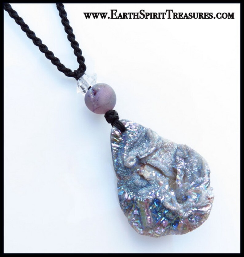 K&ouml;nnte beinhalten: Halskette mit einem gro&szlig;en, irisierenden, grau-blauen Steinanh&auml;nger und einer schwarzen Kordel. Der Anh&auml;nger ist mit einer lila Perle und einem klaren Kristall verbunden. Die Halskette wird vor wei&szlig;em Hintergrund pr&auml;sentiert. Text: www.EarthSpiritTreasures.com