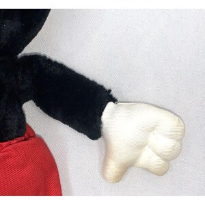 May include: A black and red plush toy Mickey Mouse with a white glove. The toy is made of soft, fuzzy fabric.