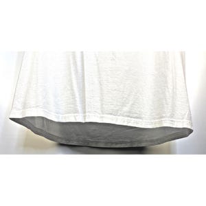 May include: A white t-shirt with a curved hemline. The fabric appears to be slightly textured, with subtle variations in tone. The bottom hem is a darker shade of gray.