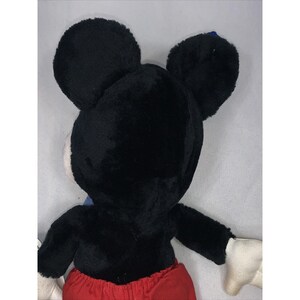 Puede incluir: Juguete de peluche Mickey Mouse negro y rojo con orejas grandes. El juguete est&aacute; de espaldas a la c&aacute;mara.