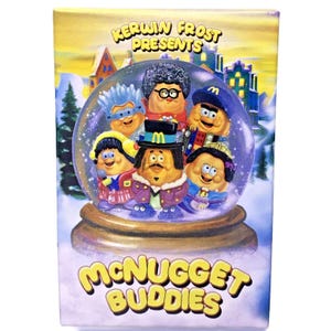 May include: A snow globe featuring the Mcnugget Buddies characters from the McDonald's restaurant chain. The globe is surrounded by a winter scene with snow-covered houses and trees. The text "Kerwin Frost Presents" is at the top of the globe, and the text "Mcnugget Buddies" is at the bottom.