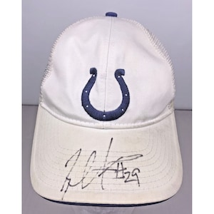 May include: White mesh baseball cap with a blue horseshoe logo and a black signature on the front. The signature reads "Peyton Manning 28".
