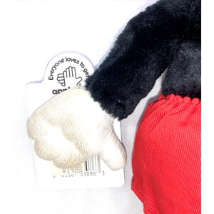 May include: A plush black and red Mickey Mouse toy with a white glove. The toy is holding a thumbs down gesture. The toy has a tag that says "Everyone loves to get along" and has a price tag of $14.99.