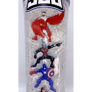 May include: A clear plastic tube containing four small action figures of superheroes. The figures are of Captain America, Ant-Man, Falcon, and a fourth figure that is partially obscured. The figures are all in different poses and are made of plastic.