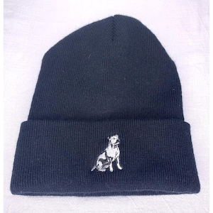 May include: A dark blue beanie with a white embroidered image of a dog on the front.