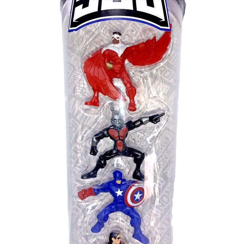 Op de afbeelding: Een doorzichtige plastic buis met vier kleine actionfiguren van superhelden. De figuren zijn Captain America, Ant-Man, Falcon en een vierde figuur dat gedeeltelijk verborgen is. De figuren staan in verschillende poses en zijn gemaakt van plastic.
