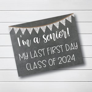 May include: Black chalkboard sign with white text that reads "I'm a senior! My last first day Class of 2024". The sign has a string of brown and white pennants across the top.