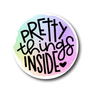 May include: A round sticker with a watercolor background in shades of pink, purple, blue, and green. The sticker features the text "Pretty things inside" in black lettering with a small heart at the end.