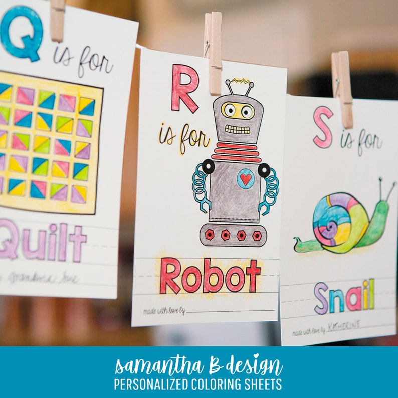 May include: Three white paper coloring sheets hanging from wooden clothespins. The sheets feature the letters Q, R, and S with illustrations of a quilt, a robot, and a snail. Each sheet includes the text is for and a blank line for a name.
