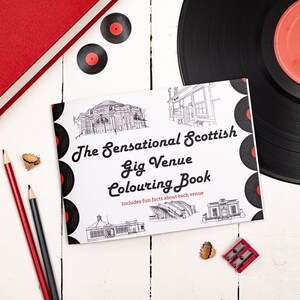 May include: A white colouring book with a black and white illustration of a building on the cover. The title of the book is "The Sensational Scottish Gig Venue Colouring Book" and it includes the text "Includes fun facts about each venue".
