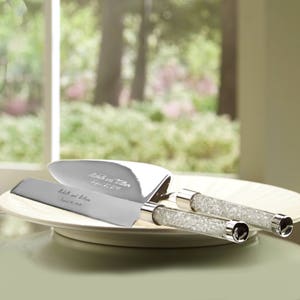 May include: A silver cake cutting set with crystal handles. The knife and server are engraved with the names "Rich and Kim" and the date "September 17, 2017".