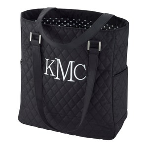 May include: Black quilted tote bag with a white monogram "KMC" on the front. The bag has two top handles and a zippered pocket on the side.