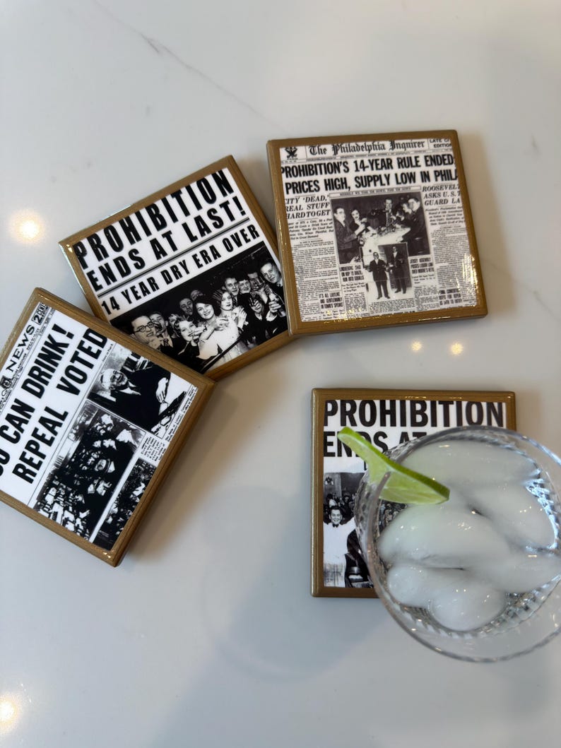 Op de afbeelding: Vier vierkante onderzetters met een glanzende afwerking, elk voorzien van zwart-witte vintage krantenknipsels over het einde van de drooglegging. De koppen luiden PROHIBITION ENDS AT LAST, 14 YEAR DRY ERA OVER en YOU CAN DRINK! REPEAL VOTED.