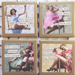 May include: Set of four gold-framed coasters with humorous sayings and vintage illustrations of women with cocktails. The sayings include "Save water, drink vodka", "I'm way too sober for this crap", "Well played tequila, well played", and "Drinking is cheaper than therapy".