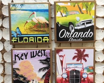 Puede incluir: Cuatro posavasos cuadrados con marcos dorados y pósters de viajes vintage de Florida. El posavasos superior izquierdo presenta un pájaro blanco con un pico largo y una mariposa azul. El posavasos superior derecho presenta un automóvil verde con un techo convertible amarillo. El posavasos inferior izquierdo presenta una puesta de sol rosa y púrpura con palmeras y el texto "Experience Key West". El posavasos inferior derecho presenta un automóvil rojo con una tabla de surf y palmeras.