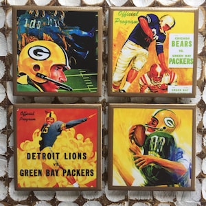 May include: Set of four square coasters featuring vintage football game art. Each coaster has a gold border and depicts players in action, with team names like "Green Bay Packers" and "Detroit Lions" visible.