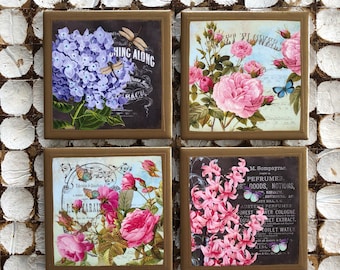 May include: Set of four square ceramic tiles with floral designs and vintage text. The tiles feature hydrangeas, roses, and hyacinths in shades of pink, purple, and white. The text on the tiles includes "Hing Along", "Deft Flowers", "Marais", and "Perfumes, Dry Goods, Notions".