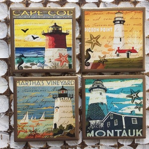May include: Four square coasters with a nautical theme. Each coaster features a lighthouse with a different design and text. The coasters are made of ceramic and have a glossy finish. The text on the coasters includes the names of the locations: Cape Cod, Pigeon Point, Martha's Vineyard, and Montauk.