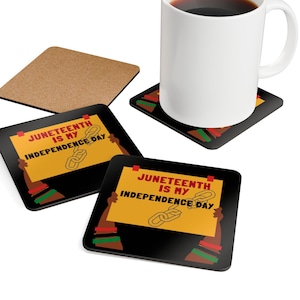 May include: A white ceramic mug filled with a dark liquid sits on a square coaster. The coaster has a black background with a yellow sign that reads "Juneteenth is my Independence Day." Additional coasters with the same design are visible.