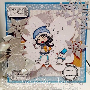 May include: A handmade Christmas card featuring a cartoon girl with a blue hat and a snowman. The card has a silver snowflake design and the text "Merry & Bright" and "Merry Christmas".