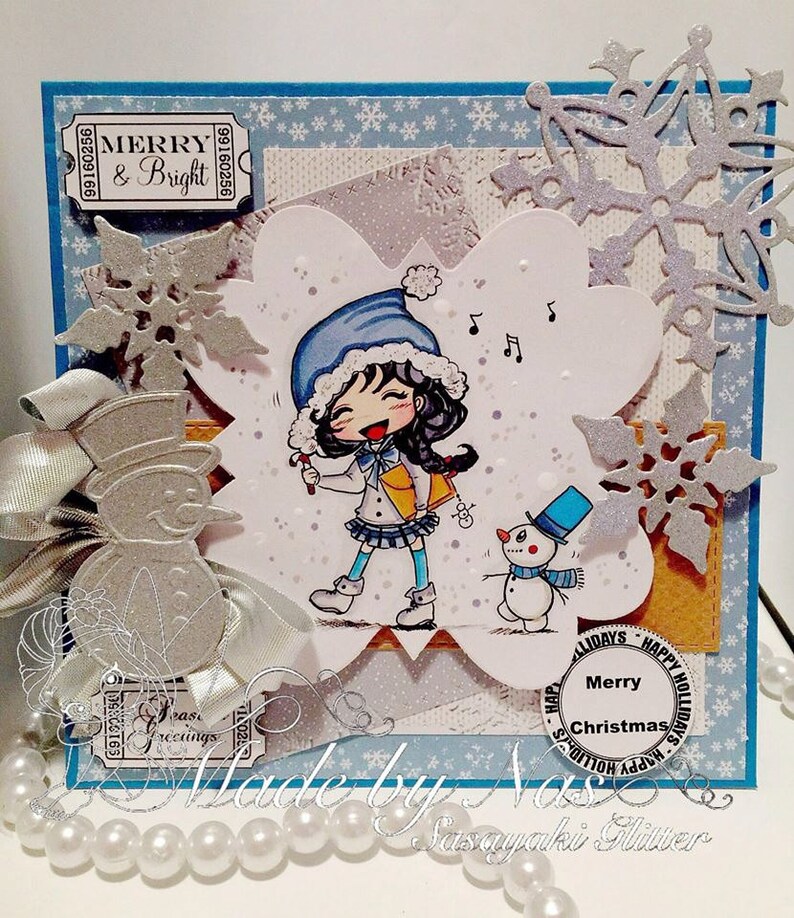 May include: A handmade Christmas card featuring a cartoon girl with a blue hat and a snowman. The card has a silver snowflake design and the text "Merry & Bright" and "Merry Christmas".