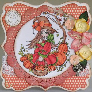 Puede incluir: Una tarjeta hecha a mano con una bruja con un vestido rojo y verde que sostiene una cesta de calabazas. La tarjeta tiene un fondo de lunares y un borde de encaje blanco. La tarjeta tambi&eacute;n presenta un peque&ntilde;o &aacute;rbol y flores.