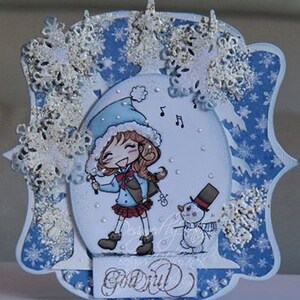 May include: A blue and white winter-themed card with a girl in a blue hat and red scarf holding a musical note. The card has a snowman and snowflakes on it. The text on the card says "Go Girl".