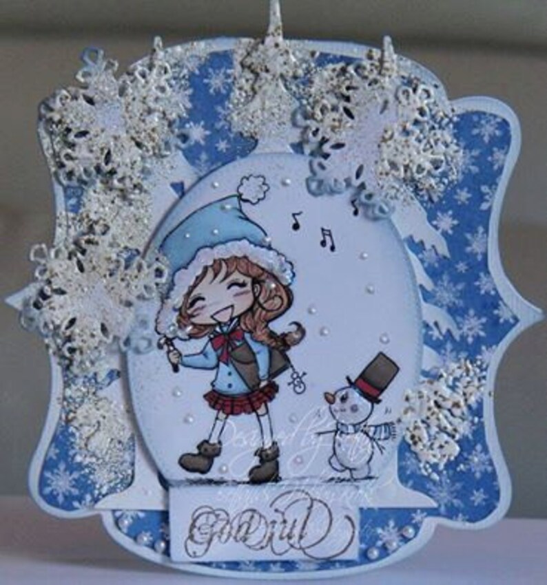 May include: A blue and white winter-themed card with a girl in a blue hat and red scarf holding a musical note. The card has a snowman and snowflakes on it. The text on the card says "Go Girl".