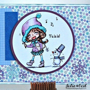 May include: A purple-clad girl with a blue hat sings "Fa la la!" to a snowman with a top hat and scarf against a background of blue and purple snowflakes.