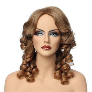 May include: A brown wig with long, curled hair styled in two large ringlets on either side of the head. The wig is on a mannequin head with a neutral makeup look.
