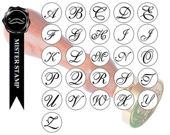 May include: A set of 26 round wax seal stamps featuring the letters of the alphabet in a cursive font. The stamps are arranged in five rows, with the first row containing the letters A through E, the second row containing the letters F through J, and so on. The stamps are all black and white and are set against a white background.