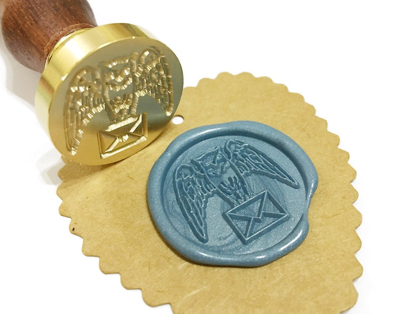Puede incluir: Un sello de cera dorado con un dise&ntilde;o de un b&uacute;ho que lleva un sobre. El sello se utiliza para crear un sello de cera azul con el mismo dise&ntilde;o.