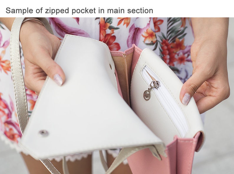 May include: A white and pink handbag with a zippered pocket. The pocket is open and the zipper pull is visible. The bag has a gold chain strap.