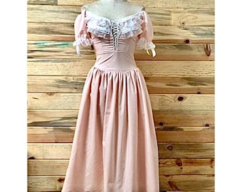 May include: A pink off-the-shoulder dress with a white lace bodice and a full skirt. The dress has a lace-up front and short puffed sleeves.
