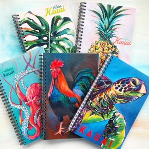 Könnte beinhalten: Fünf verschiedene Spiralblöcke mit bunten Illustrationen und dem Text "Aloha Kauai" auf jedem Cover. Die Illustrationen zeigen ein Monstera-Blatt, eine Ananas, einen Hahn, einen Oktopus und eine Meeresschildkröte.