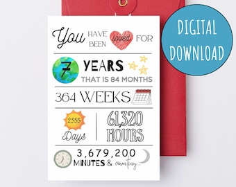 Op de afbeelding: Een witte kaart met zwarte tekst en illustraties ter ere van 7 jaar. De kaart luidt "Je bent 7 jaar lang geliefd geweest, dat is 84 maanden, 364 weken, 2.555 dagen, 61.320 uur, 3.679.200 minuten en het gaat door".