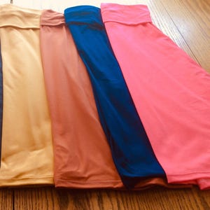 May include: Five different colored fabric skirts, from left to right: black, mustard yellow, burnt orange, navy blue, and hot pink.