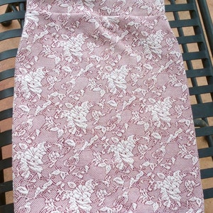 May include: A pink and white skirt with a floral pattern. The skirt is made of a stretchy fabric and has a fitted silhouette.