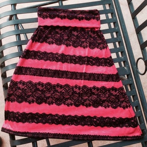 May include: A pink and black striped skirt with black lace trim. The skirt is made of a soft, stretchy fabric and has a comfortable fit.
