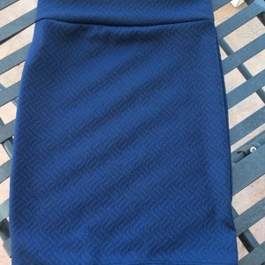 May include: A dark blue mini skirt with a textured, herringbone pattern. The skirt has a simple, fitted silhouette.